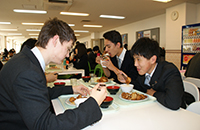 小杨和留学生伙伴在学生食堂吃午饭。他们在用英语热烈交谈。